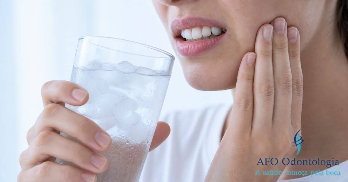 Pessoa com expressão de dor ao ingerir alimento gelado — sensibilidade dental ao frio ou calor, Taboão da Serra