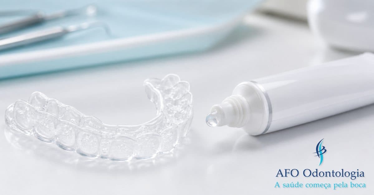 Moldeira de clareamento dental com gel branqueador ao lado de tubo de gel profissional sobre superfície branca